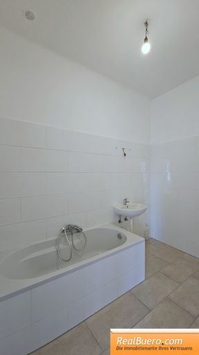 Badezimmer mit Wanne, Handwaschbecken und Waschmaschinenanschluss