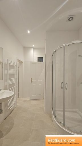 Badezimmer mit Dusche Handwaschbecken und Waschmaschinenanschluss