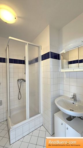 Badezimmer mit Dusche, Handwaschbecken, Waschmaschinenanschluss