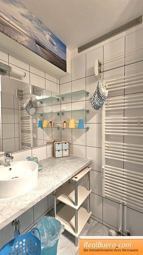 Badezimmer mit Dusche, Handwaschbecken, Handtuchtrockner, Waschmaschineneanschluss