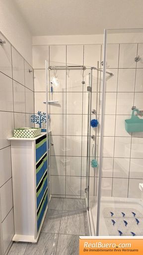 Badezimmer mit Dusche, Handwaschbecken, Handtuchtrockner, Waschmaschineneanschluss