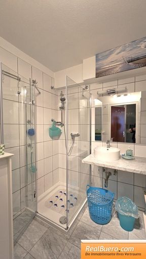 Badezimmer mit Dusche, Handwaschbecken, Handtuchtrockner, Waschmaschineneanschluss