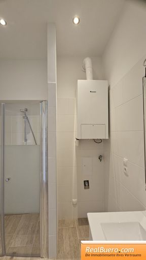 Badezimmer mit Dusche Handwaschbecken und Waschmaschinenanschluss