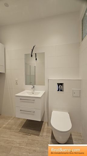 Badezimmer mit Dusche Handwaschbecken und Waschmaschinenanschluss